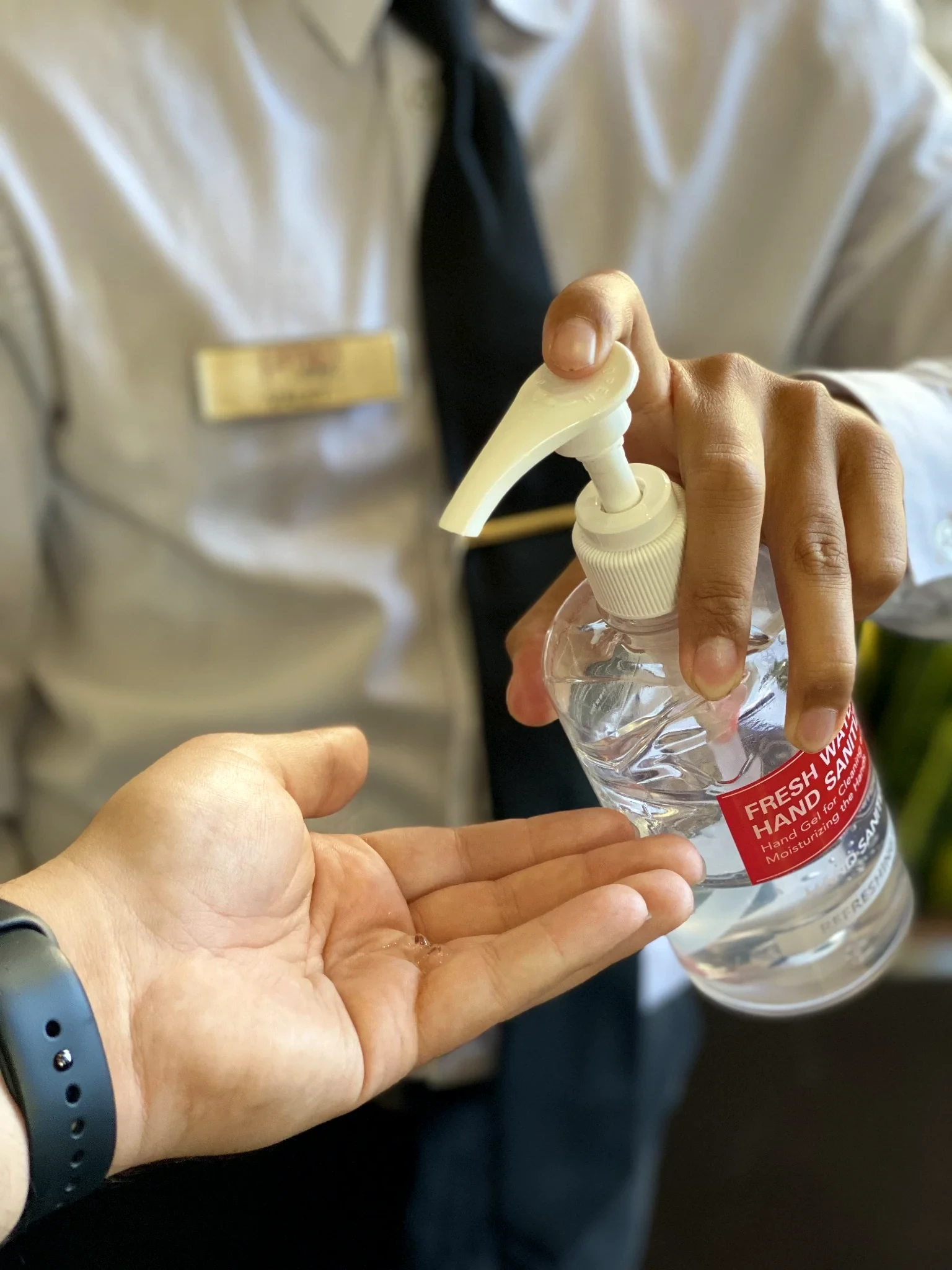 PMSA attendant dispensing hand sanitizer to a patient at a hospital entrance