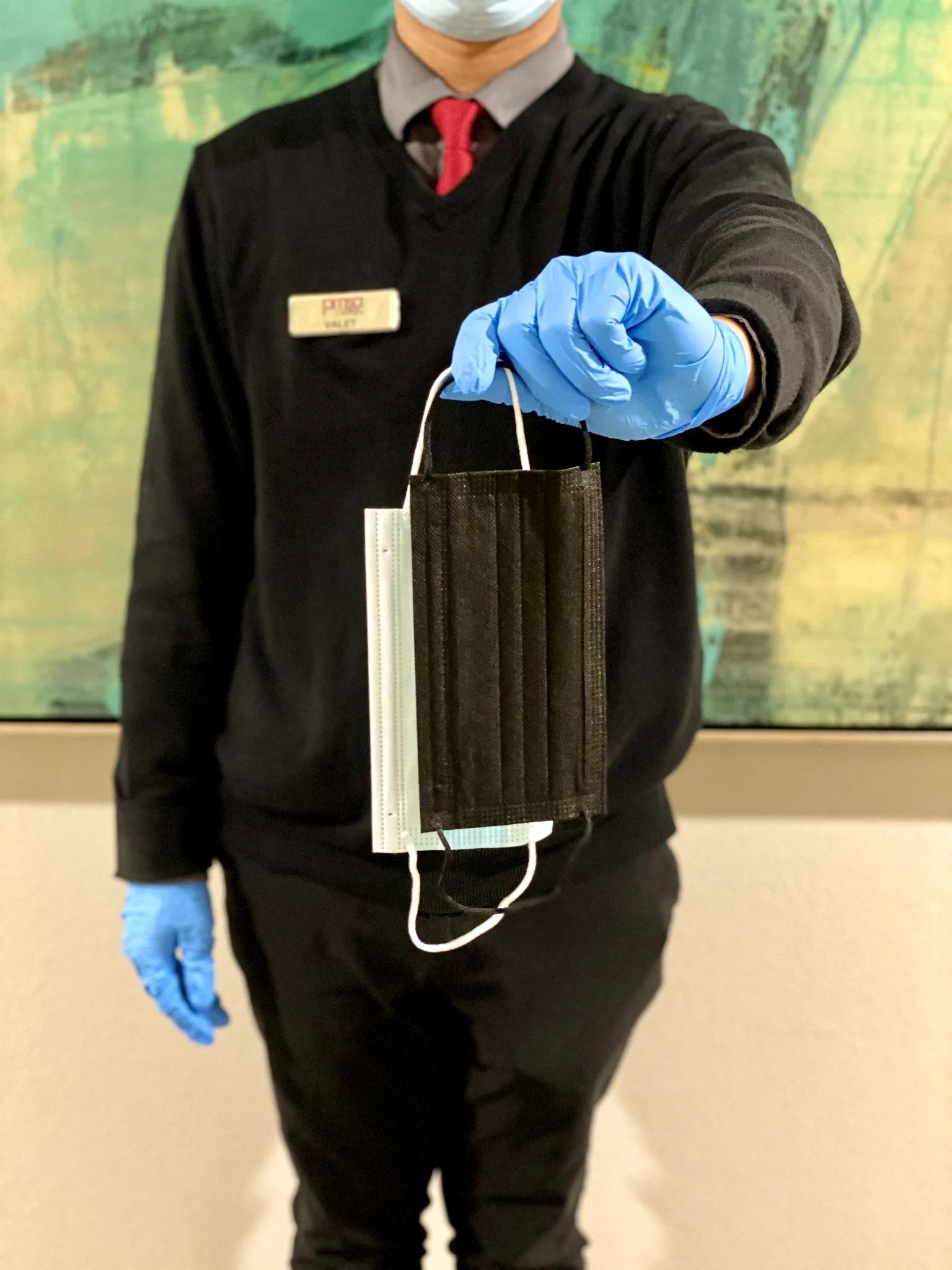 PMSA attendant in uniform holding packaged face masks toward the camera