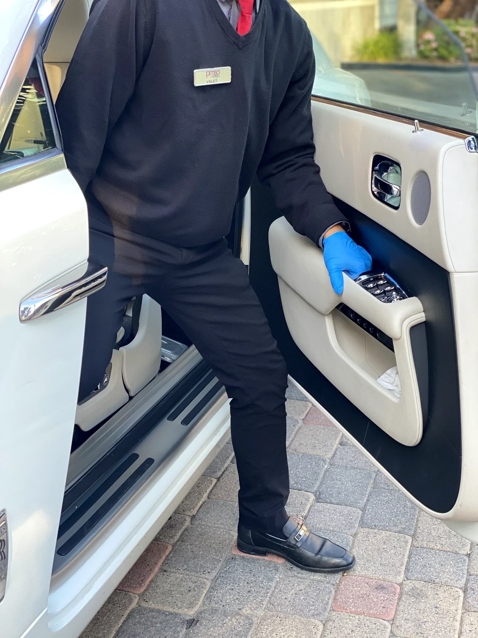 PMSA attendant opening the door of a white Rolls-Royce showing cream leather interior