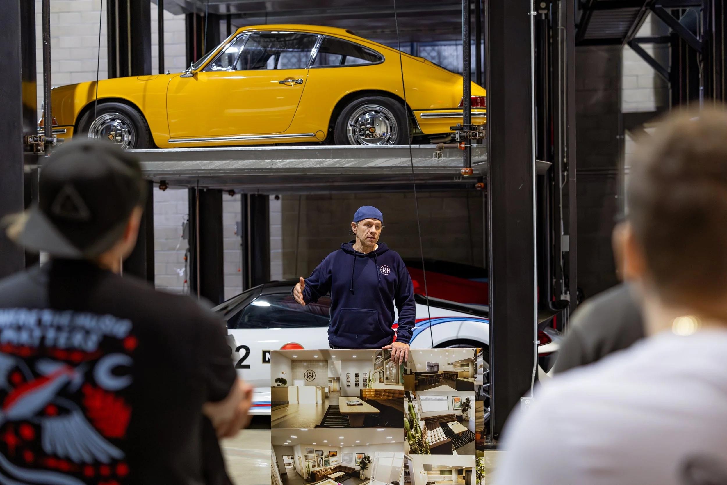Matt Farah presenting Westside Collector Car Storage to guests with a yellow Porsche on a ParkPlus Quad Stacker lift