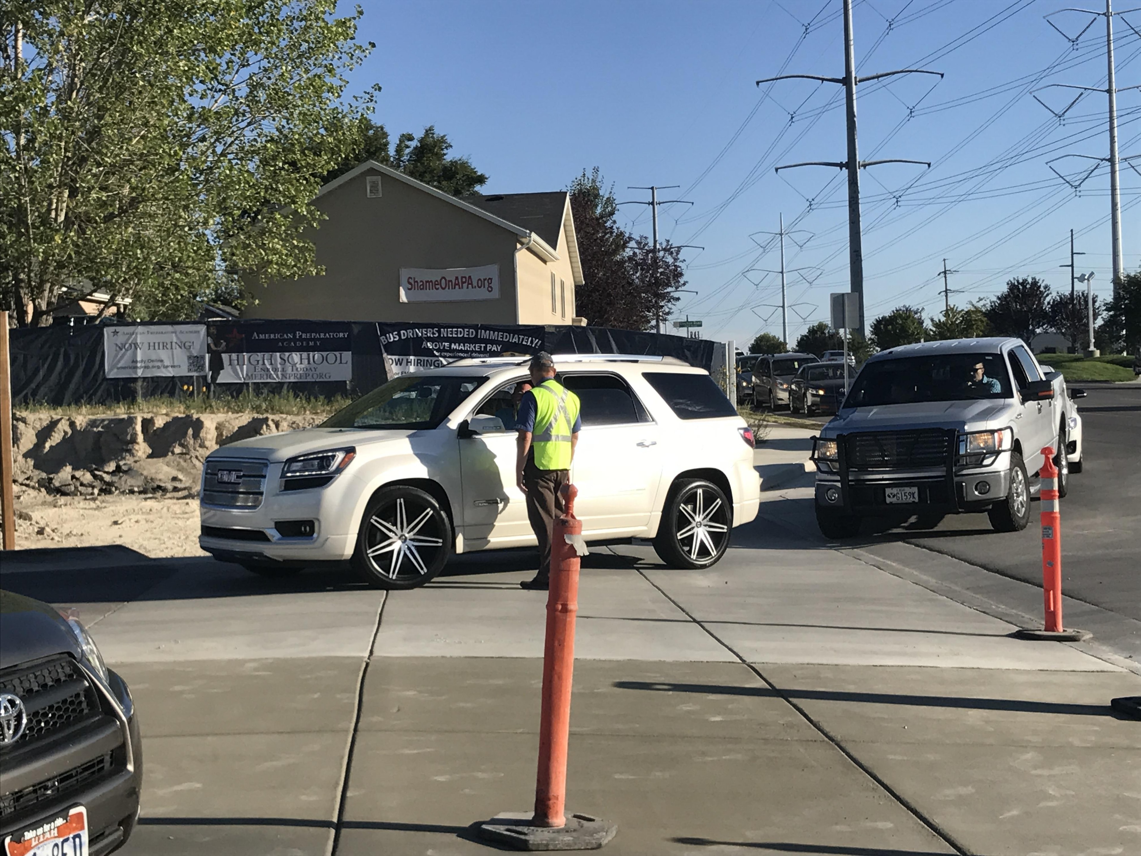 PMSA traffic attendant in high-visibility vest directing vehicles at a school drop-off lane