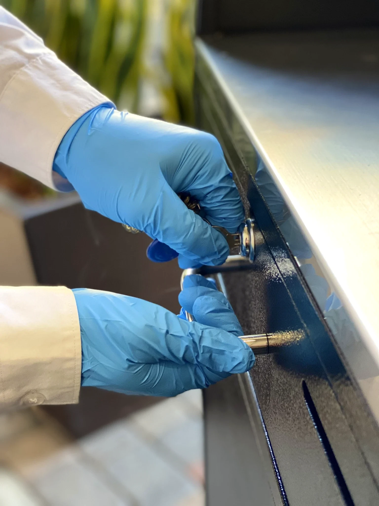 Blue-gloved PMSA attendant cleaning a car door handle